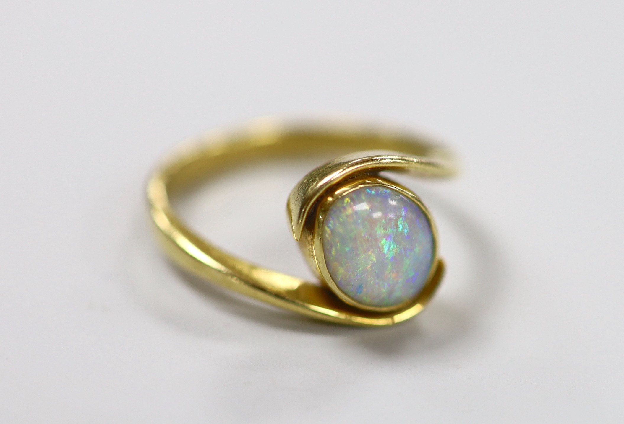 An 18ct and single stone oval white opal set ring, with crossover shoulders, size Q, gross weight 5.6 grams.